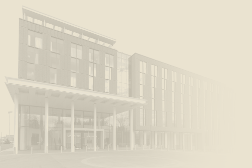 A modern multi-story building with glass windows and a covered entrance, set against a pale, desaturated background.