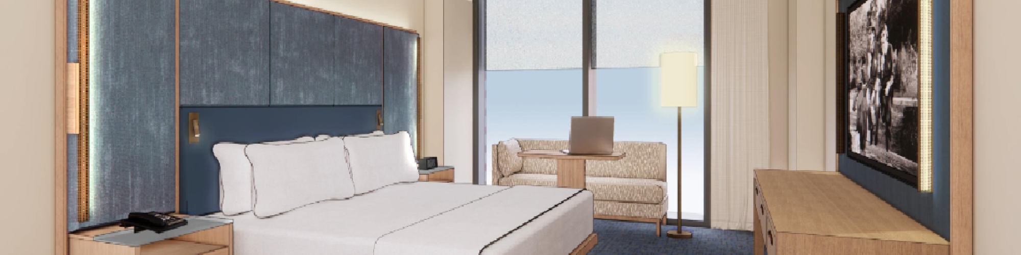 A modern hotel room with a large bed, nightstand, sofa, lamp, and TV, facing floor-to-ceiling windows offering an ocean view.