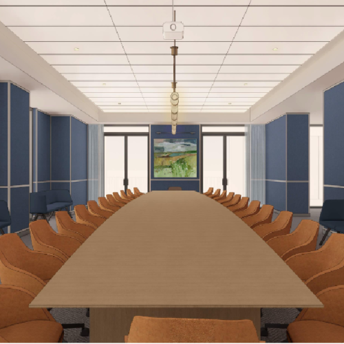 A long oval conference table with tan chairs, blue paneled walls, and a wall-mounted screen at the far end in a bright, modern meeting room.