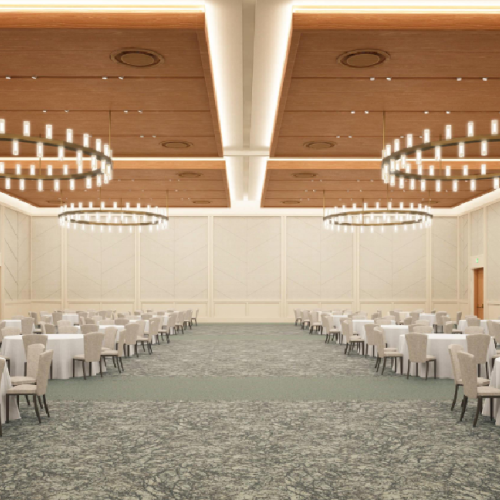 A spacious banquet hall with round tables, white tablecloths, cushioned chairs, and large circular chandeliers above, arranged in neat rows.