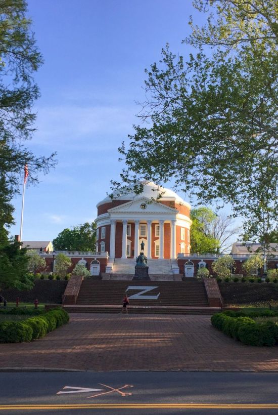 A grand neoclassical pavilion sits atop a stepped plaza, flanked by trees and arranged paths in a peaceful park setting.