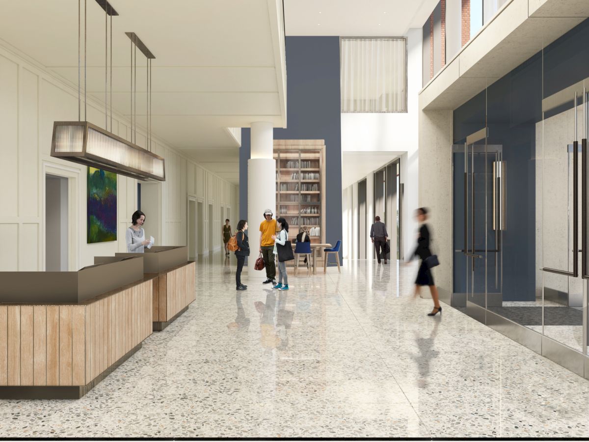 A modern office lobby with a reception desk, tall windows, polished terrazzo floor, and people walking or chatting near glass walls.