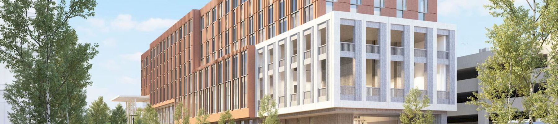 A modern multi-story building with a white grid-like facade on the lower section and a warm brown brick upper block, set beside a landscaped park.