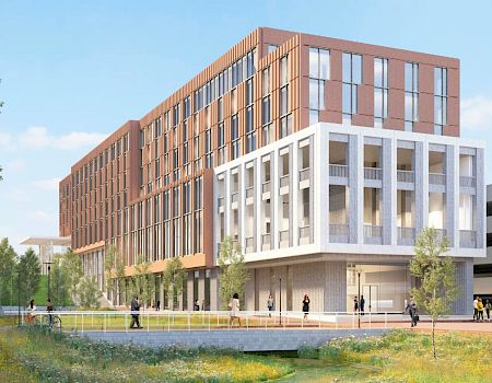 A modern multi-story building with a white grid-like facade on the lower section and a warm brown brick upper block, set beside a landscaped park.