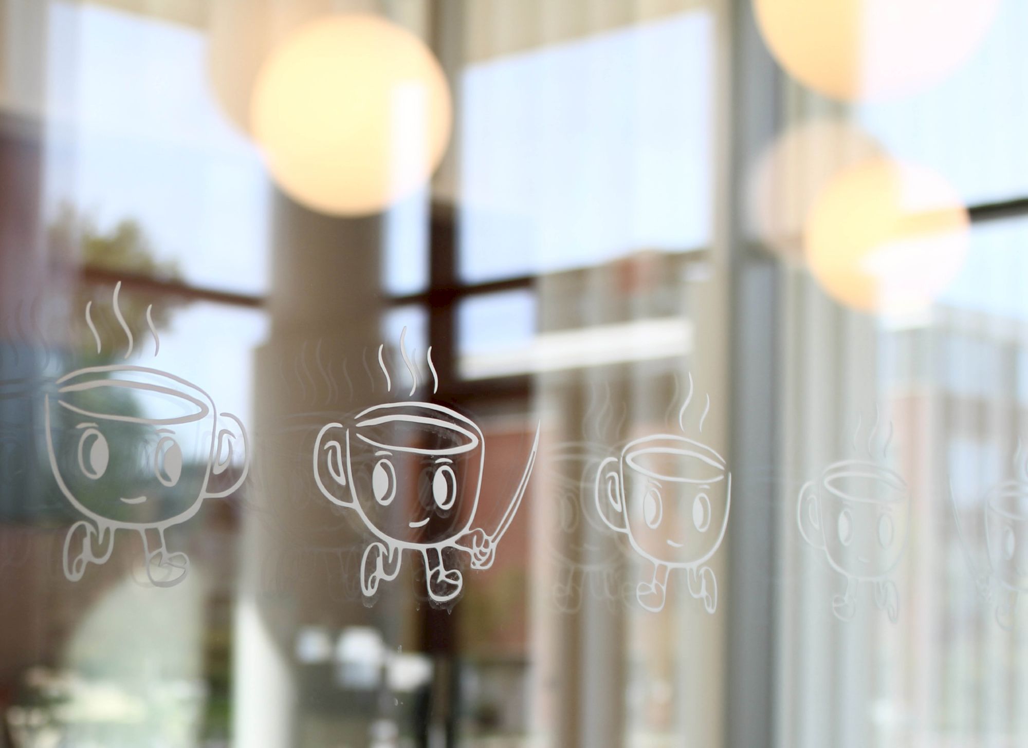 Cartoon coffee cups with little faces drawn on a window, on a blurred cafe backdrop with warm bokeh lights in the background.