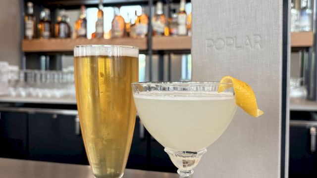 Two drinks on a bar: a tall beer and a elegant cocktail with a lemon twist, set against a well-stocked back bar.