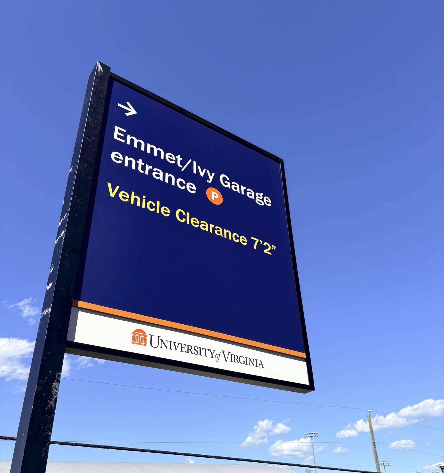 A large campus sign shows directions to the Emergency/IV Garage Entrance and Vehicle Clearance 7&rsquo;2&rdquo;, with the University of Virginia logo beneath, under a clear blue sky.
