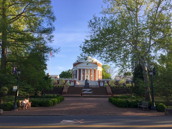 A sunny park scene with a classic white-and-orange building, wide steps, trees, and flags.
