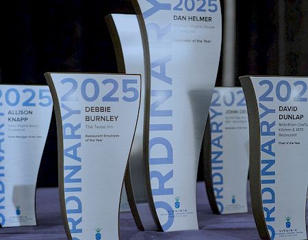 A row of 2025 award plaques and banners on display for a Virginia Hospitality Association event, including Restaurant Employee and Chef of the Year.