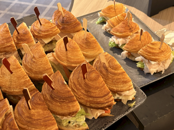 Skewered croissant sandwiches with lettuce, chicken/turkey, and cheese on a serving tray.